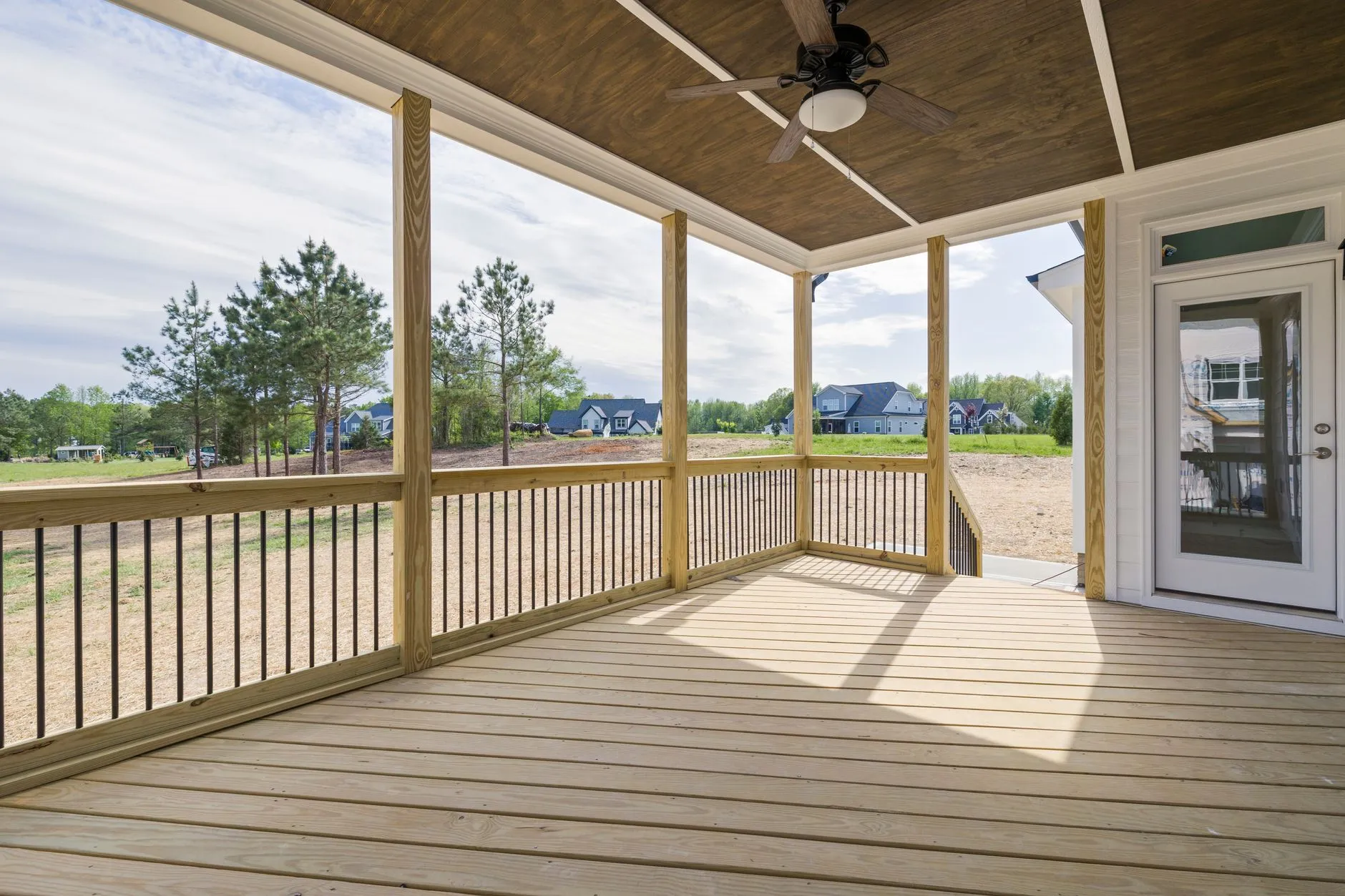 Newly built covered deck with wooden posts and railings overlooking an open backyard